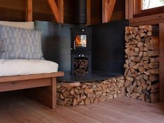 a wood burning stove in the corner of a room next to a bed with pillows on it