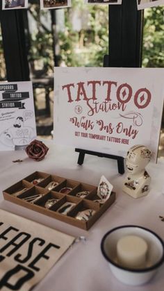 a table topped with lots of different types of tattoos and other items on display in front of a sign that says tattoo parlor