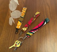 three keychains with different designs on them sitting on top of a wooden table