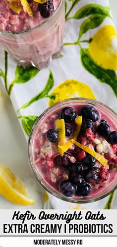 two glasses filled with blueberries and lemons on top of a table