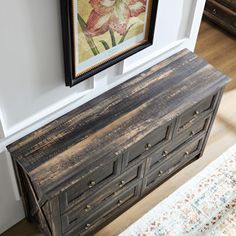 an old dresser is next to a painting on the wall