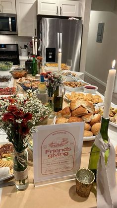 a table full of food and drinks with flowers in vases on the table next to it