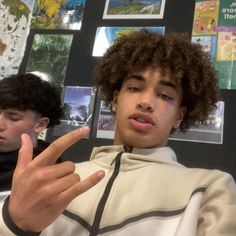 two young men sitting at a table with their fingers in the shape of a peace sign