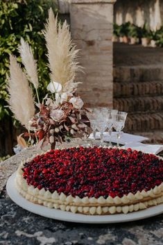 an elaborately decorated cake sits on a table with wine glasses and flowers in the background