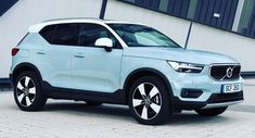 a light blue volvo suv parked in front of a building with black and white accents