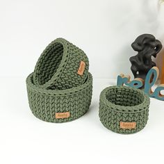 two knitted baskets sitting next to each other on a white surface with wooden letters