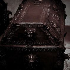 an ornately carved wooden box sitting on top of a floor next to a wall