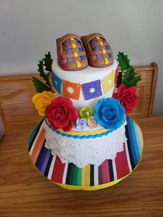 a multicolored cake with shoes on top and flowers in the middle is being held up by someone's hand