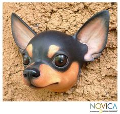 a black and brown dog head mounted on the side of a wall with dirt behind it