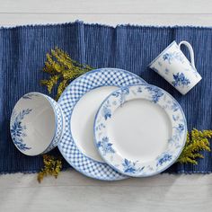 blue and white dishes are arranged on a place mat