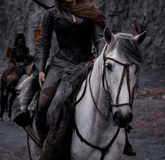 a woman riding on the back of a white horse next to a man in armor