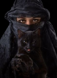 a woman wearing a black veil and holding a cat in her lap with the caption,