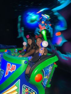 two girls are riding on a roller coaster at an amusement park in the night time