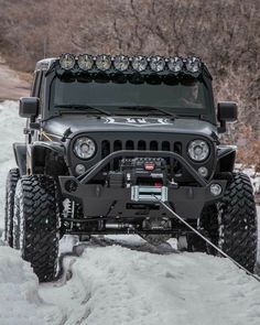 a jeep is parked in the snow with its front lights turned on and headlamps down