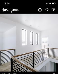 a white room with black railings and windows on the wall, along with wood flooring