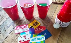 four red cups are sitting next to each other on a table with cards and candy