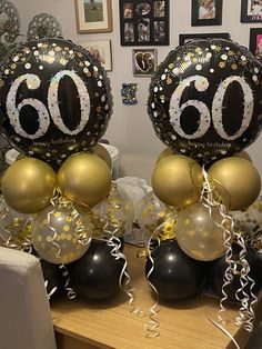 two black and gold balloons with the number 60 on them are sitting on a table