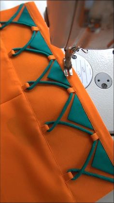 an orange piece of fabric being sewn on with a sewing machine in the background