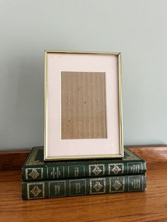 two books sitting on top of each other next to a framed photo in a gold frame