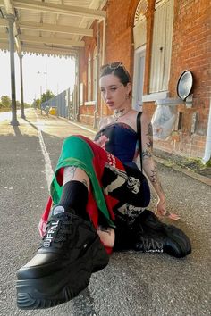 A women sitting on the floor at a train station. One foot is positioned close to the camera, her black platform sneaker are the focus point of the picture. She´s wearing a multicolored dress, she has sliked back hair,+I126 sunglasses on her head and tattoos on her arms,legs, neck and face. Metallic Look, Be The One, All Black Outfit, Platform Sneaker, Sneakers Outfit, Sneakers Online