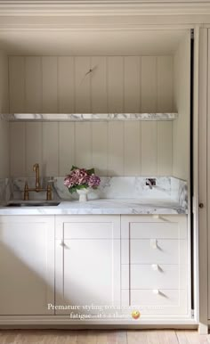 a kitchen with white cabinets and marble counter tops, along with an open shelving unit