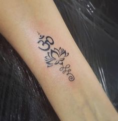 a small tattoo on the arm of a woman with an om symbol in black ink