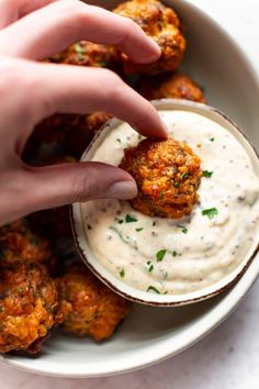 a person dipping some kind of food in a bowl with ranch dressing on the side