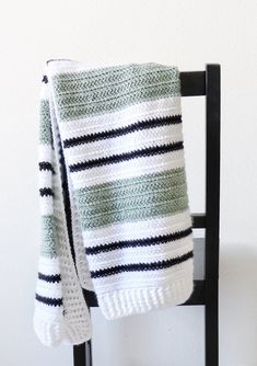 a green and white blanket sitting on top of a chair