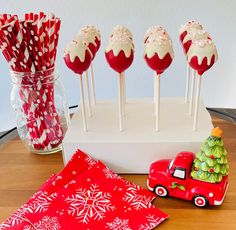 red and white cake pops with snowflakes on them next to a christmas tree