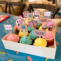 cupcakes in a box on a table with other decorations and decorating items