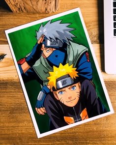 an image of two anime characters on a wooden table next to a laptop and pen