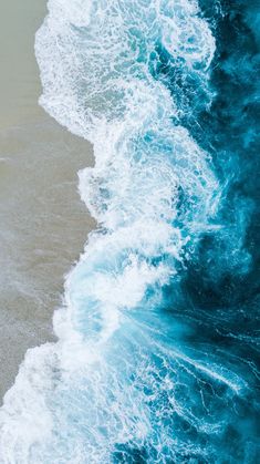 the water is blue and foamy on top of the sand near the shore line