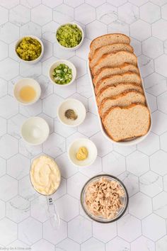 the ingredients to make this sandwich are laid out on a white counter top, including bread, mayonnaise and other condiments