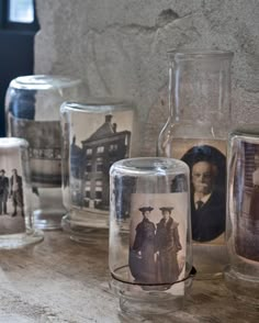 some glass jars with pictures on them sitting on a counter