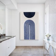 a painting hangs on the wall above a sink in a bathroom with marble countertops