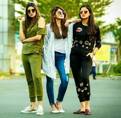 three young women standing next to each other on the street with their arms around one another