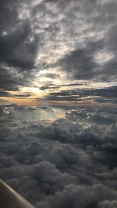 the view from an airplane looking down on clouds and sun rays in the sky above