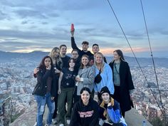 a group of people standing on top of a hill next to each other with the city in the background