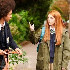 two young people standing next to each other on a sidewalk with trees in the background