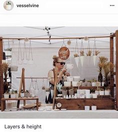 a woman standing in front of a table filled with pots and planters next to a sign that says, layers & height