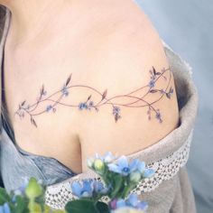 a woman's shoulder with small blue flowers on the left side of her chest