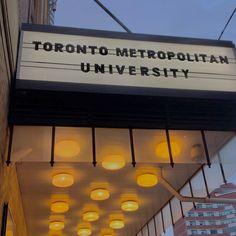 a sign that reads toronto metropolitan university hanging from the side of a building with lights on it