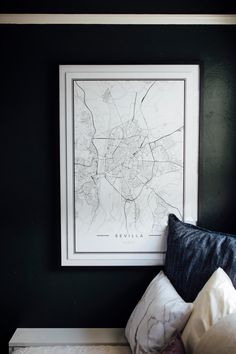 a black and white map hangs on the wall above a bed with pillows in front of it