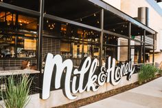 the entrance to milk and honey restaurant with people sitting outside