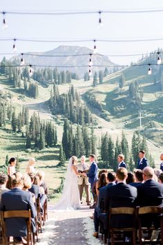 a bride and groom standing at the end of their wedding ceremony with mountains in the background