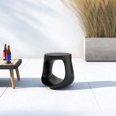 a black table sitting on top of a white tiled floor next to a planter