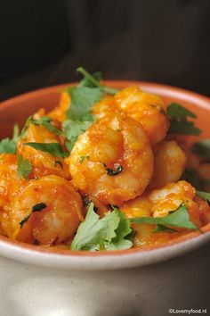 a bowl filled with shrimp and cilantro on top of a table