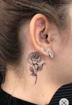 a woman's ear with a rose tattoo on it