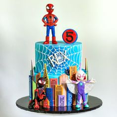 a spiderman birthday cake with the number five on top and superhero figures around it