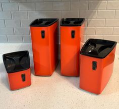 four orange trash cans sitting on top of a counter